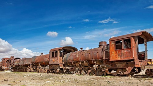 Rusty old trains on dry ground under blue skies, old rusty locomotives at the train cemetery near