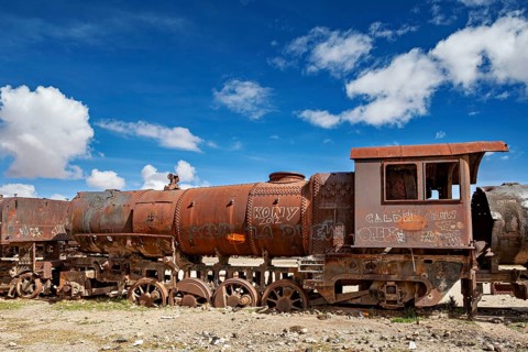 Abandoned and rusty locomotive with graffiti under a dramatically cloudy sky, old rusty locomotives