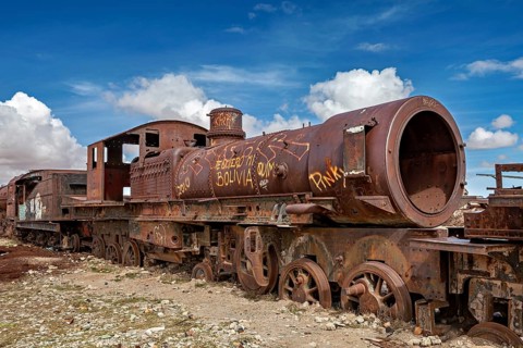 Rustic, graffiti-decorated locomotive in an open, cloudy landscape, old rusty locomotives at the