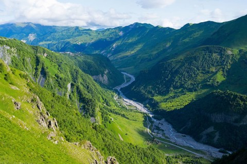Breathtaking panorama of green mountains and a river valley surrounded by rich nature, landscape