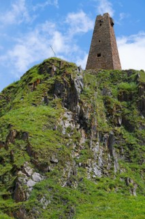 Historic ruin of a tower on a green rock face under a blue sky, Zion Tower, Sioni, Georgian