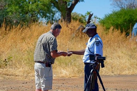 A police officer talks to a man on the side of the road in a rural setting, man must pay fine for