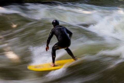 Surfers standing on Eisbach wave in the English Garden Munich, Upper Bavaria, Germany