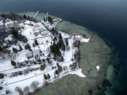 The wintry and snowy Mainau island in Lake Constance with the pier and the baroque Mainau Castle,