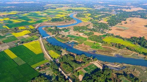 An aerial view reveals a gently curving river winding through the countryside, its silvery surface