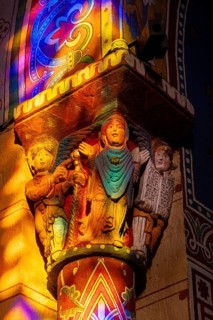 Issoire. Pillar (The Annunciation made to Mary) . The figures are illuminated by colorful light