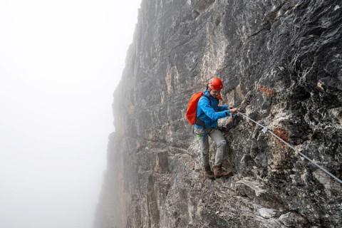 Mountaineers on a steep rock face on the Via Ferrata Oliva Detassis via ferrata in fog, steep