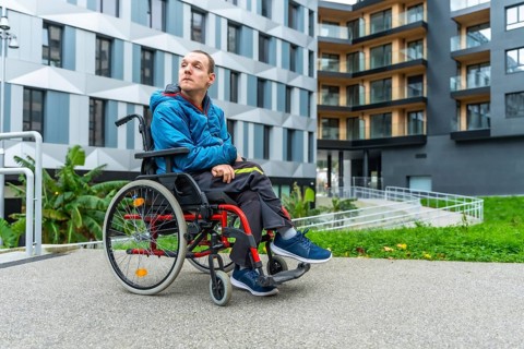 Disable adult man sitting in a wheelchair while looking away, outdoors in a modern urban