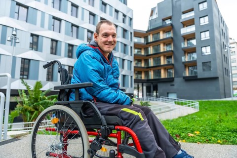 Smiling man with a disability navigating a modern urban environment in his wheelchair, highlighting