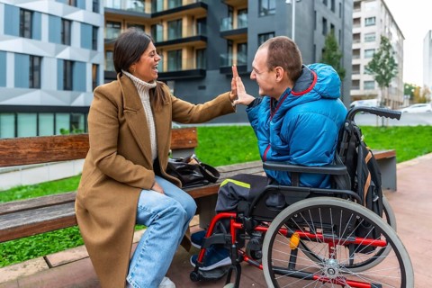 Smiling woman and man with a physical disability celebrating with a high five, reflecting themes of