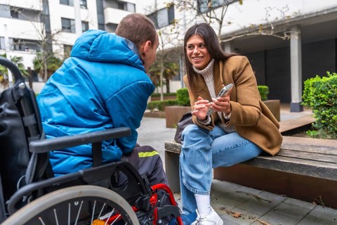 Woman and man with disability in wheelchair engaging in an inclusive outdoor conversation, sharing