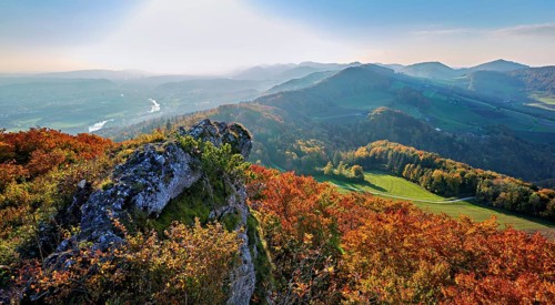 View of an autumnal forest from the Gisliflue, behind the Jura foothills with Wasserfluh and