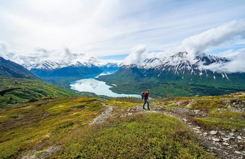 Climbers on a hiking trail, Slaughter Ridge Trail, view of snowy mountains and turquoise lake Kenai