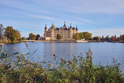 Castle, lake Burgsee, reed (Phragmites australis), trees, bushes, car bridge and pedestrian bridge,