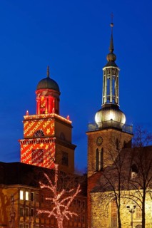 The Christmassy illuminated town hall tower and the illuminated church tower of St. John's Church