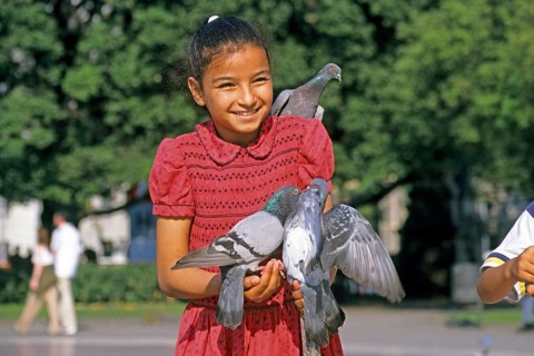 A girl holding two doves and feeding them, Placa de Catalunya, Barcelona, Spain, June 1999,