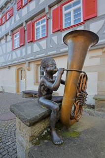 Sculpture boy with tuba by Guido Messer 1991, modern art, bronze sculpture, playing music, tuba,