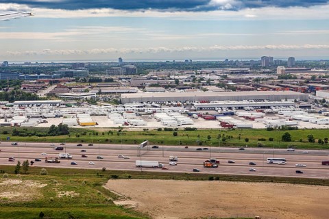 An industrial cityscape with a busy highway and overlying clouds, view from an airplane of the