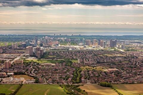 A comprehensive panorama of a city with high-rise buildings and suburbs under a cloudy sky, near