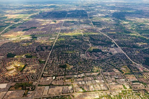 Vast urban areas with a distinctive striped pattern under a blue sky, view from an airplane of the