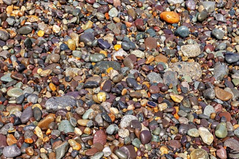 A variety of colorful pebbles of various shapes and colors form a natural texture. The colorful
