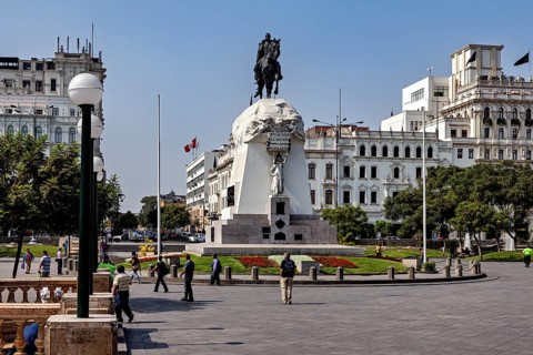 Equestrian statue surrounded by walkers, against a backdrop of colonial architecture, Downtown Lima