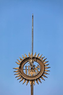 Metal sculpture with sun motif against clear blue sky, reliefs at the Basilica of St. Francis in