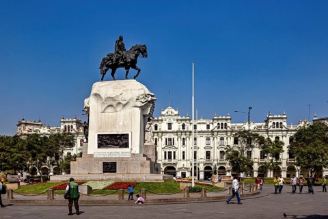 Equestrian statue in front of a flower-decorated base in a square with white buildings, Downtown