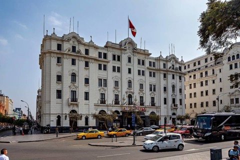 Large white building with national flag surrounded by vehicles and trees, Downtown Lima in Peru