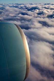 Airplane engine towering over clouds that glow at dusk, On an airplane above the clouds
