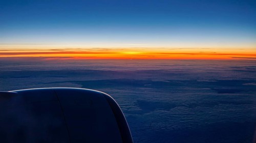 Sunset with dark sky and aircraft engine, On a plane above the clouds