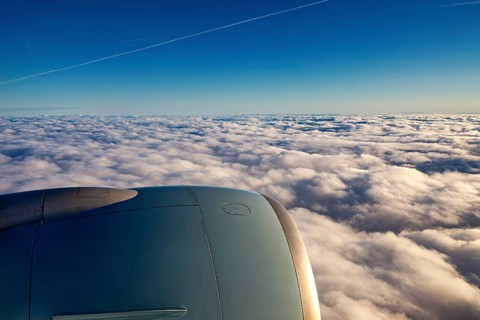View of aircraft engine above white clouds under blue sky, On an airplane above the clouds