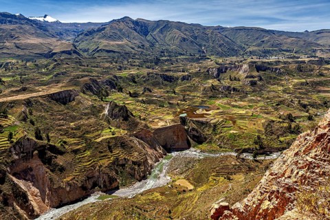 Terraced fields and a river surrounded by mountains under clear skies, the landscape of the Colca