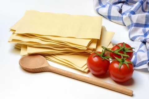 Lasagna, dried lasagna leaves with tomatoes and cooking spoon