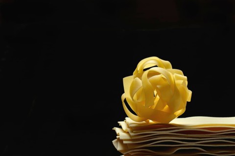 Uncooked lasagna leaves and fettuccine, noodle nest