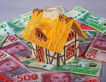 Small decorative ornamental cottage standing on Swedish 500 and 200 kronor banknotes. Symbol image