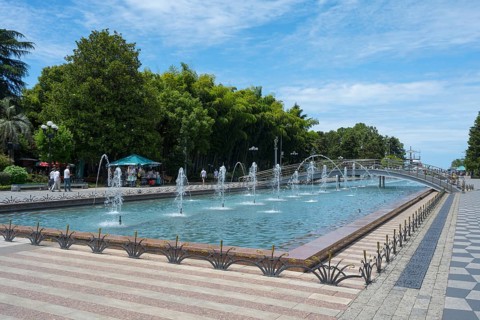 Fountain with walkway and trees in urban landscape under blue sky, Batumi Boulevard, Batumi, Black