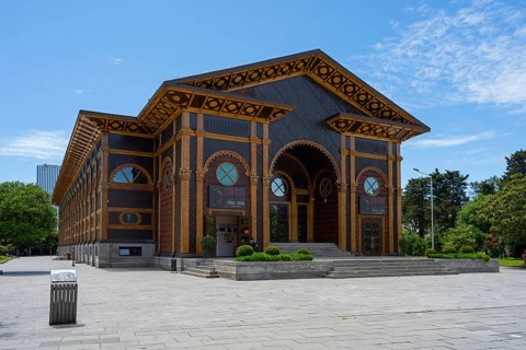 In sunlight, an artfully designed wooden building with well-kept surroundings and clear skies,