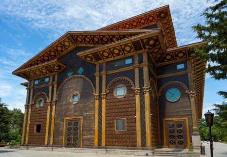 A distinctive wooden building with artistic decorations against a tranquil backdrop, Summer