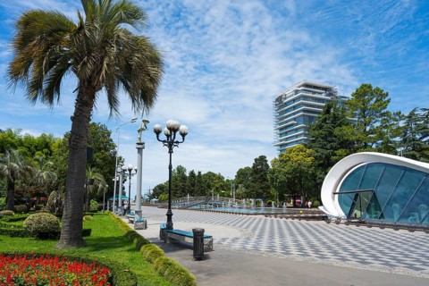 Palm trees and street lamps along a modern walkway in the urban landscape with fountain, right