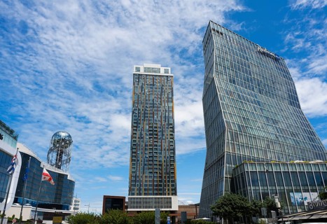 Two modern high-rise buildings with glass facades under cloudy sky, Radison Blue on the right and