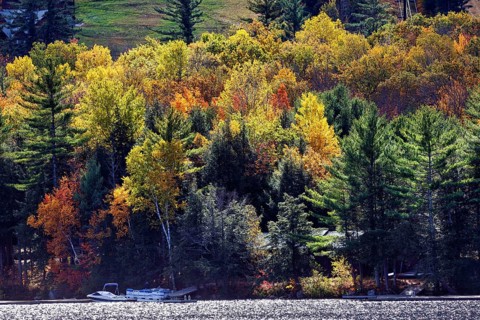 Cottage on the shore of a lake, motor boat, boat dock, autumn leaves, Indian Summer, Maine, New
