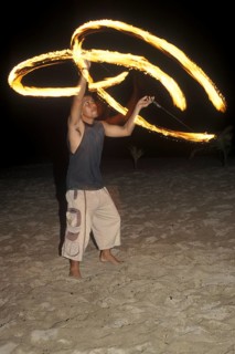 A man waves burning torches on the beach of Coral Beach Resort on the island of Ko Lanta, Thailand,