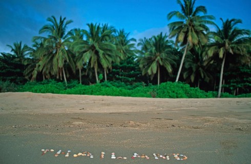 Palm trees, Thailand with shells written in the sand on the island of Ko Lanta, Thailand, December