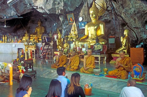 Buddha statue, monks and believers praying, Wat Tam Sua monastery near Krabi, Thailand, December