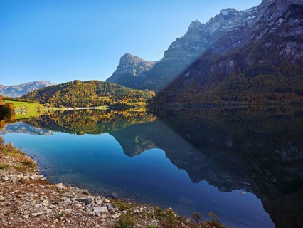 Autumn-colored forest is reflected in Obersee, Näfels, Canton of Glarus, Switzerland