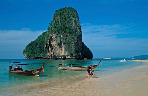 Rocks in the sea, people and longtail boats on Pranang Cave beach, two years in front of the