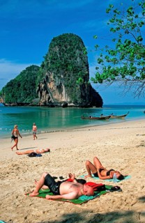Rocks in the sea, people and longtail boats on Pranang Cave beach, two years in front of the