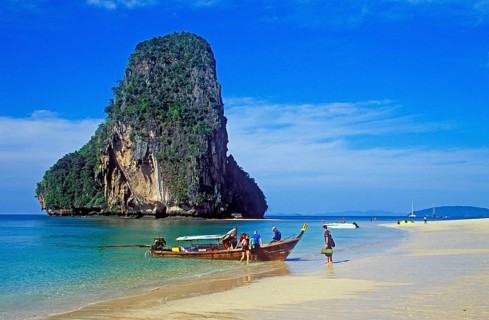 Rocks in the sea, people and longtail boat on Pranang Cave beach, two years in front of the