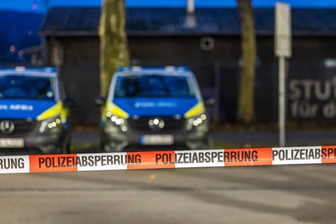 Flutter tape with the inscription police barrier. Behind them, police vehicles. Stuttgart,